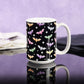 Colorful Bats Mug (15oz) at Amy's Coffee Mugs. Photo shows the mug on a glossy black tabletop with a purple wall background.