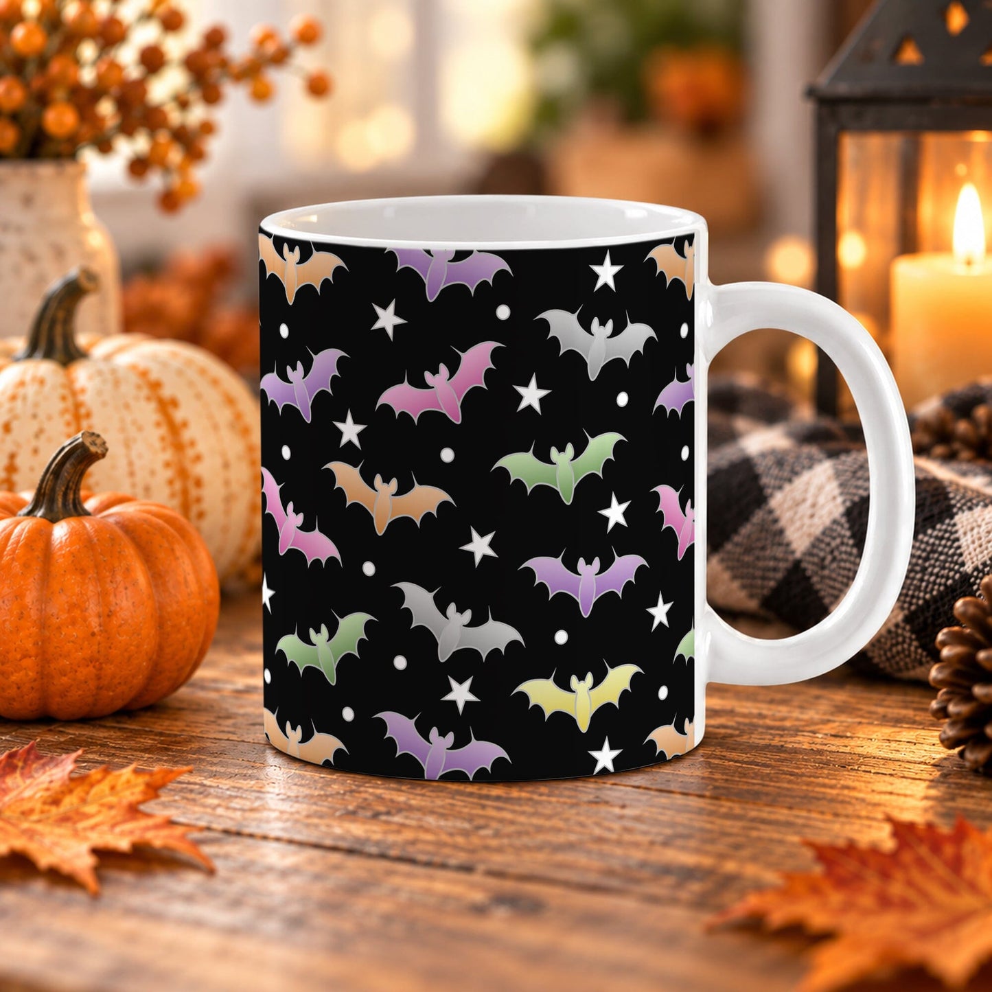 White 11 oz ceramic Halloween mug with colorful orange, purple, pink, green and silver bats, white stars and dots on a black background. The mug sits on a wooden table with fall decor around it.