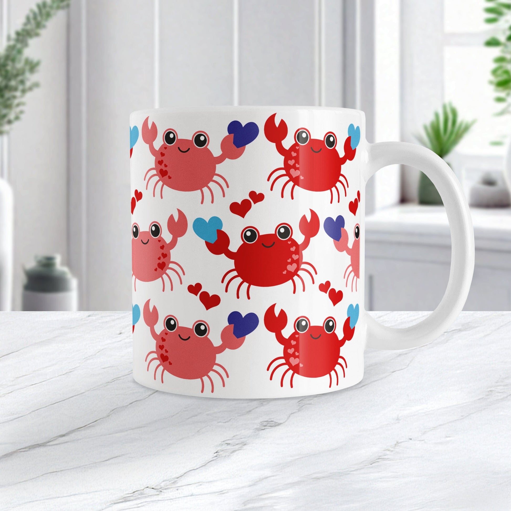 11oz white ceramic coffee mug with an adorable red crabs holding blue hearts design, on a marble countertop