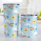 Cute Sunshine and Rainbows Tumbler Cups (20oz or 10oz) at Amy's Coffee Mugs. Stainless steel tumbler cups designed with happy and smiling yellow suns, colorful rainbows, raindrops, and clouds over a blue sky background color in a pattern that wraps around the cups. Image shows both sized cups on a table next to each other.