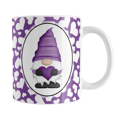 Cute White Hearts Purple Gnome Mug (11oz) at Amy's Coffee Mugs. A ceramic coffee mug designed with an adorable purple gnome in a white oval on both sides of the mug over a pattern of cute white hearts over a purple background that wraps around the mug to the handle.