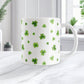 White mug with green clover pattern on a white marble surface