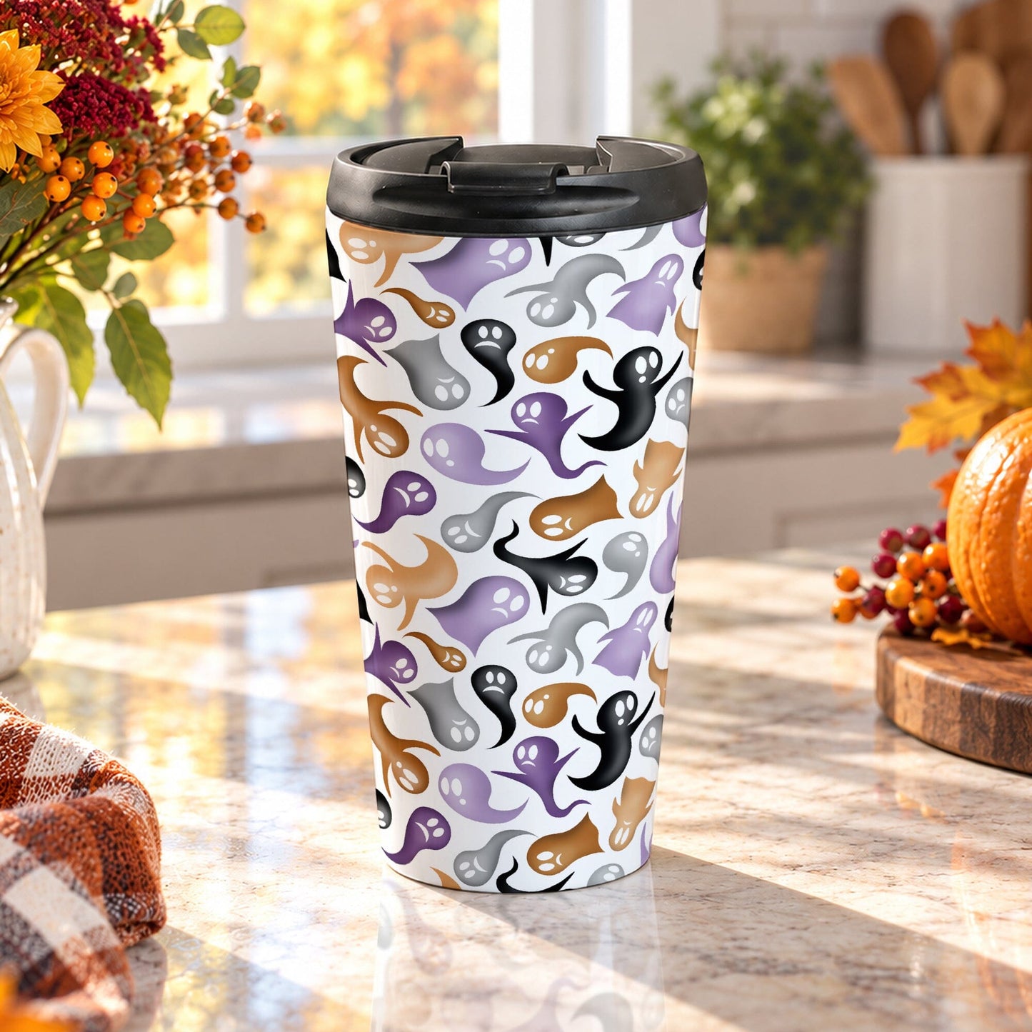 15 oz stainless steel Halloween travel mug with purple, orange, black, and gray ghosts and spirits on white with a black screw-on lid, on a marble countertop in a kitchen with fall decor including autumn plants, a pumpkin, and an orange plaid tea towel.