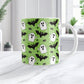 Mug with Halloween-themed design featuring ghosts, bats, and spiders on a green background.