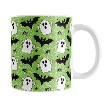 Halloween-themed mug with ghost, bat, and spider pattern on a green background