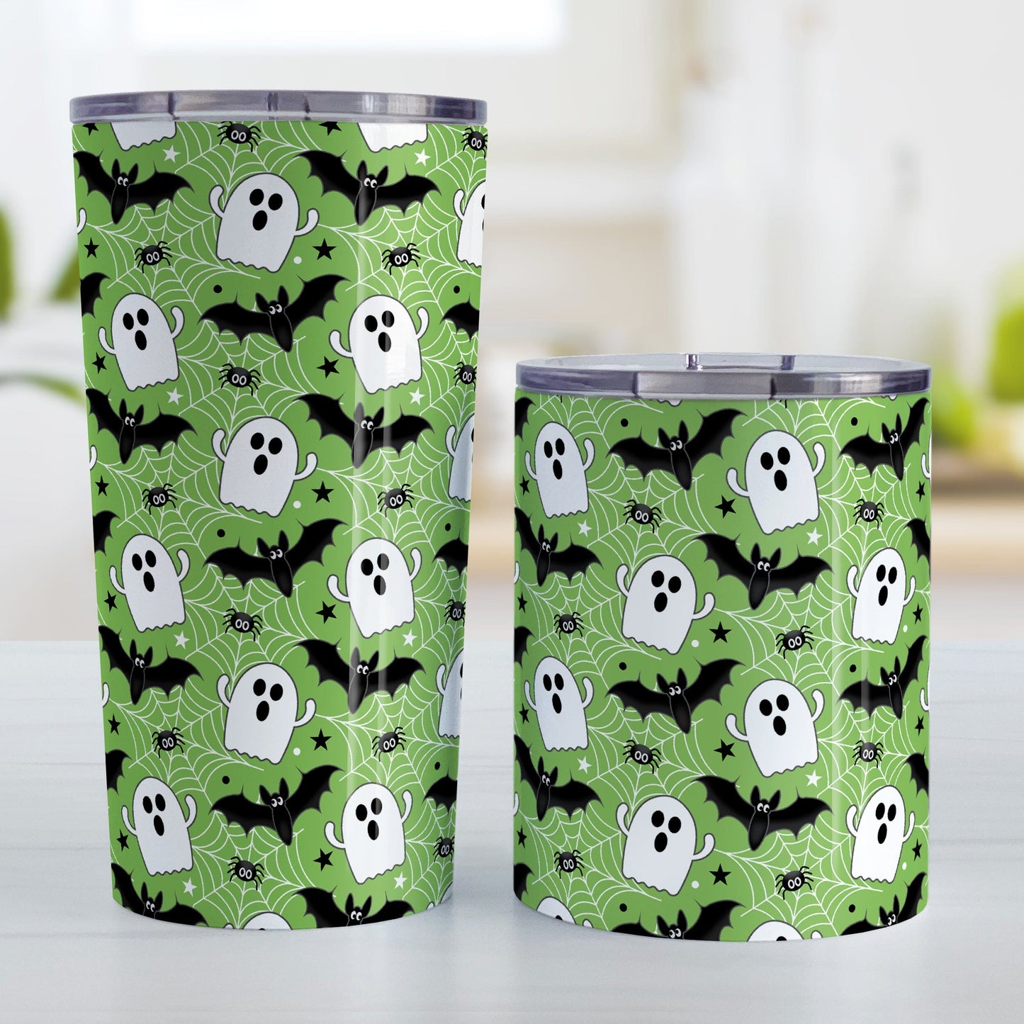 Two tumblers with Halloween-themed design featuring ghosts, bats, and spiders on a green background.