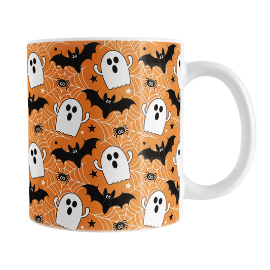 Halloween-themed mug with ghost, bat, and spider design on an orange background