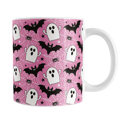 Mug with Halloween-themed design featuring ghosts, bats, and spiders on a pink background.
