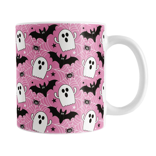 Mug with Halloween-themed design featuring ghosts, bats, and spiders on a pink background.