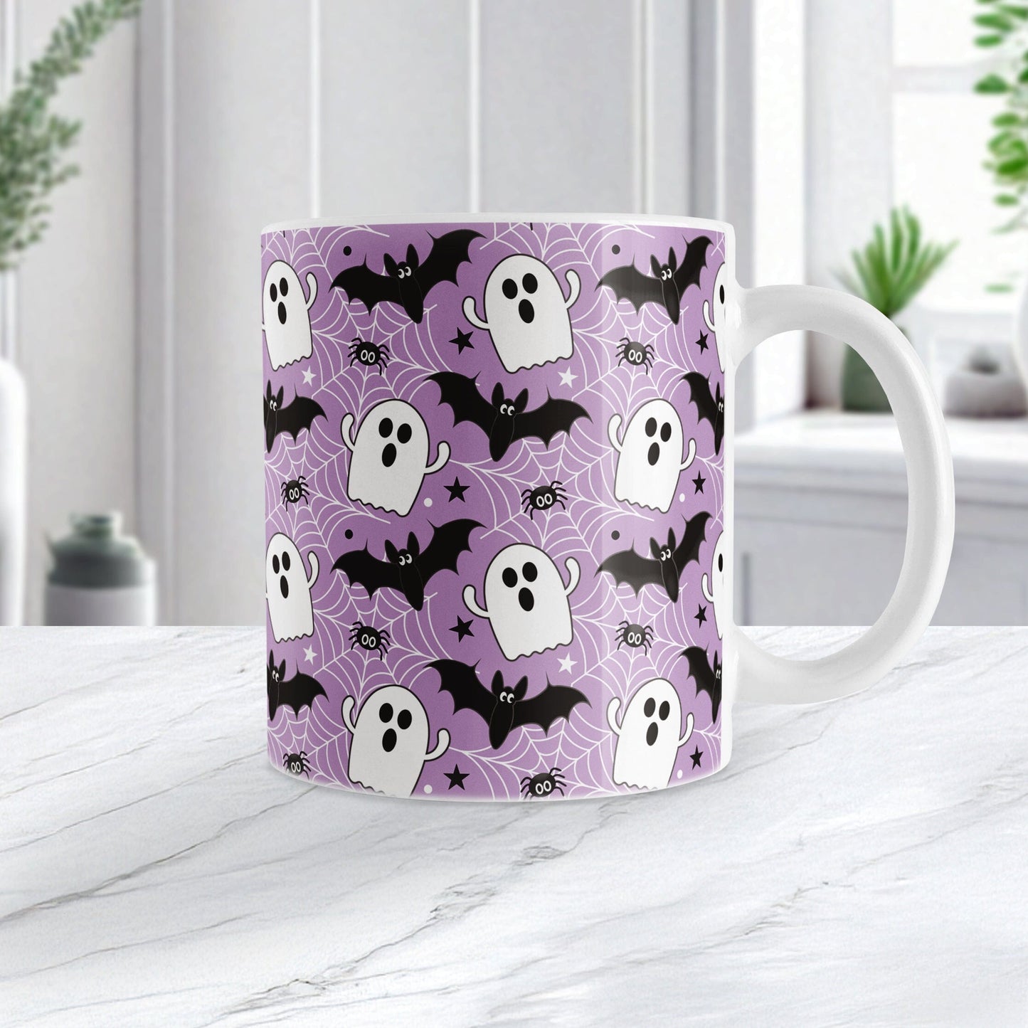 Mug with Halloween pattern featuring ghosts, bats, and spider webs on a purple background. Photo shows the mug on a marble tabletop.