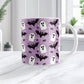 Mug with Halloween pattern featuring ghosts, bats, and spider webs on a purple background. Photo shows the mug on a marble tabletop.