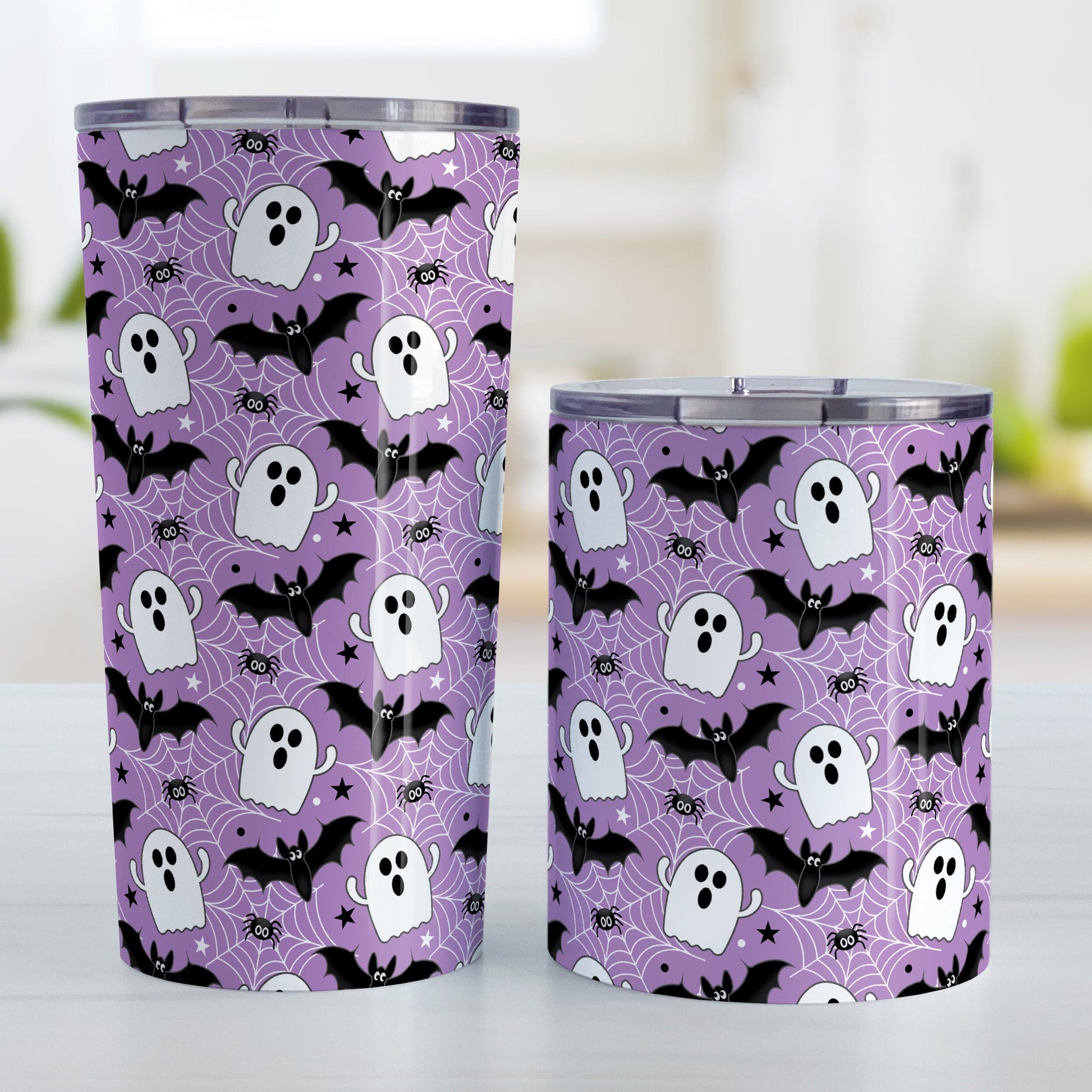Two tumblers with Halloween-themed design featuring ghosts, bats, and spider webs on a purple background.
