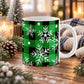 11 oz green and black buffalo plaid winter mug with large white snowflakes, smaller snowflake shapes, and scattered white round accents, shown on a wooden table with winter decor around it.