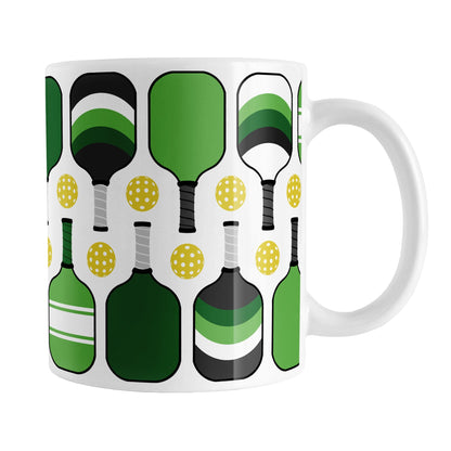Green Pickleball Mug (11oz) at Amy's Coffee Mugs. A ceramic coffee mug designed with modern green pickleball paddles and yellow balls in a pattern that wraps around the mug up to the handle.