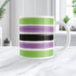 Mug with green, purple, and black stripes on a white surface.