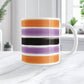 Mug with colorful Halloween-inspired stripes on a marble surface with a blurred indoor background