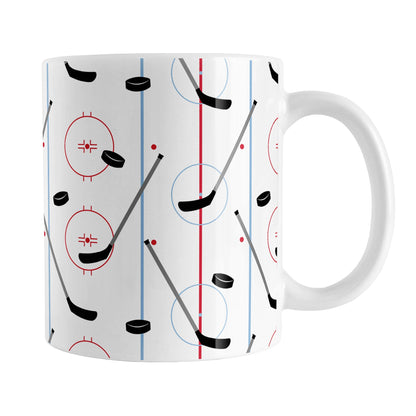 Hockey Rink Pattern Mug (11oz) at Amy's Coffee Mugs. A ceramic coffee mug designed with hockey rink red and blue lines, coupled with hockey sticks and hockey pucks, a pattern that wraps around the mug up to the handle.