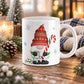 An 11 oz white ceramic mug with a Christmas gnome illustration, set on a wooden table surrounded by holiday decorations like pinecones, evergreen branches, and warm glowing candles.
