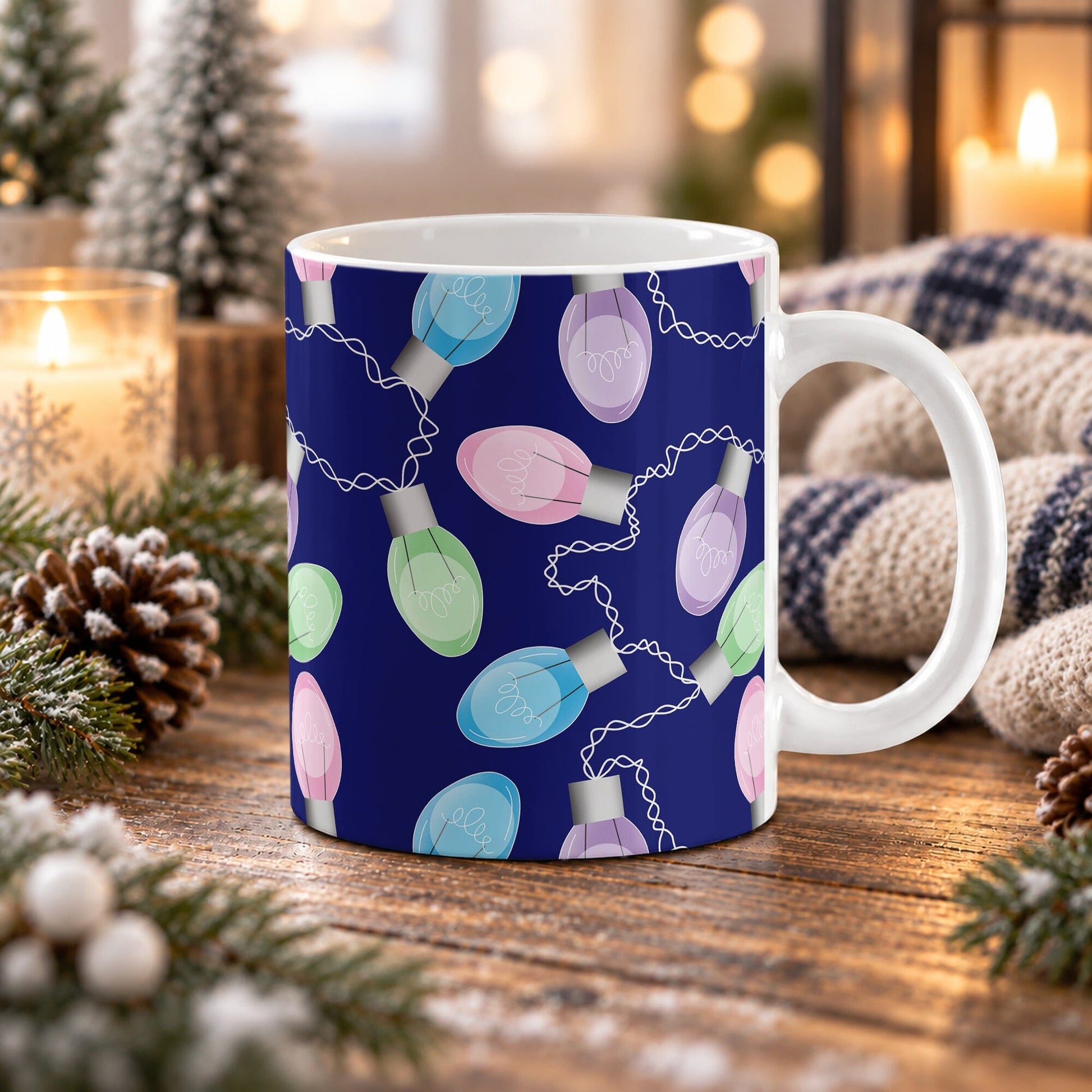 11 oz Christmas lights mug with pink, blue, green, and purple holiday bulbs over a navy blue background, on a wooden table with winter decor around it including pine cones, pine boughs, candles, and a cozy plaid blanket.
