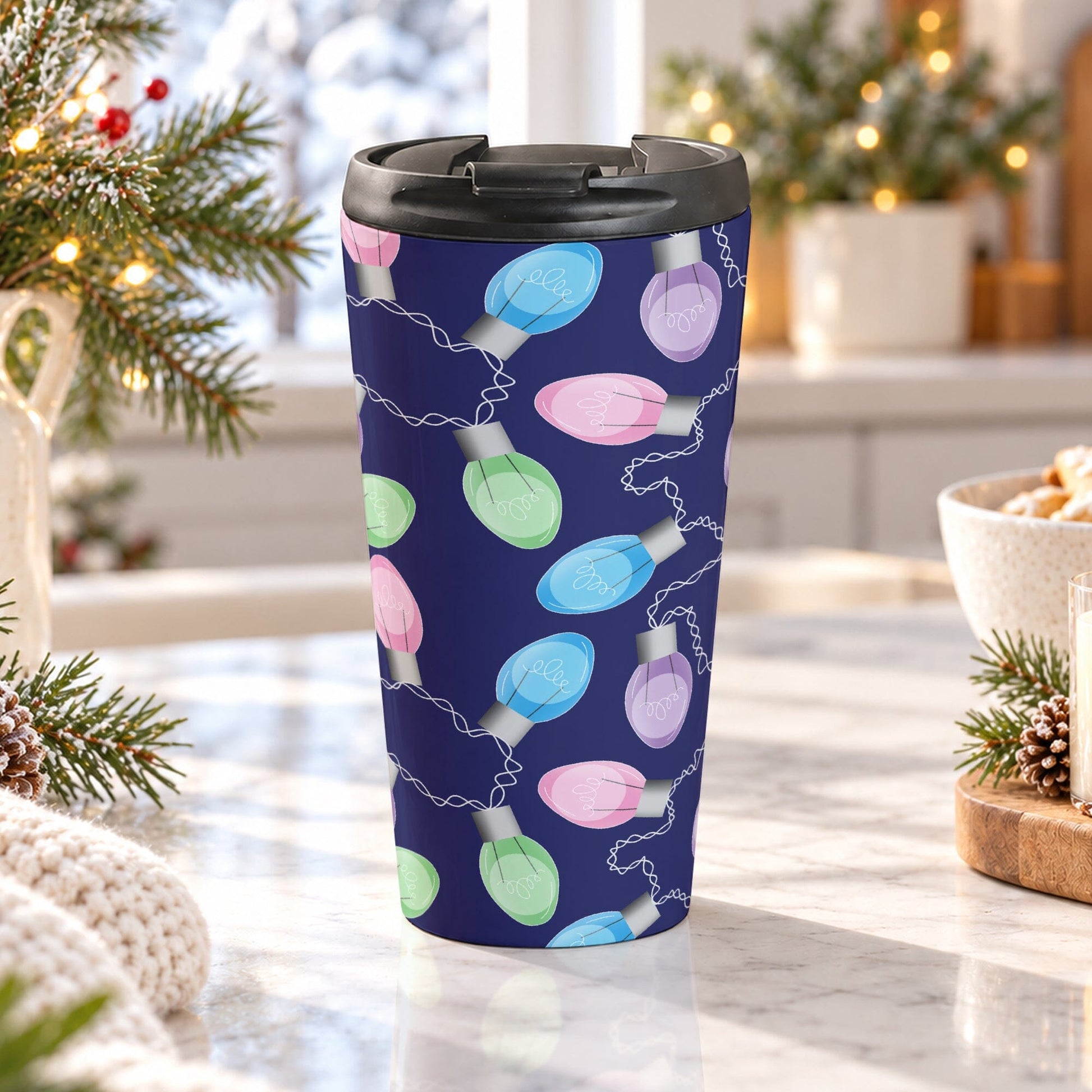 15 oz Christmas lights travel mug with pink, blue, green, and purple holiday bulbs and white cords over a navy blue background, on a granite countertop in a bright kitchen with light rustic winter decor including pine cones, pine boughs, lights, and a cozy blanket.