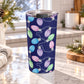 Christmas lights tumbler cup with pink, blue, green and purple bulbs on a navy background and a 20 oz insulated stainless steel body, on a granite countertop in a light rustic kitchen with pine cones, pine boughs, and a cozy blanket.