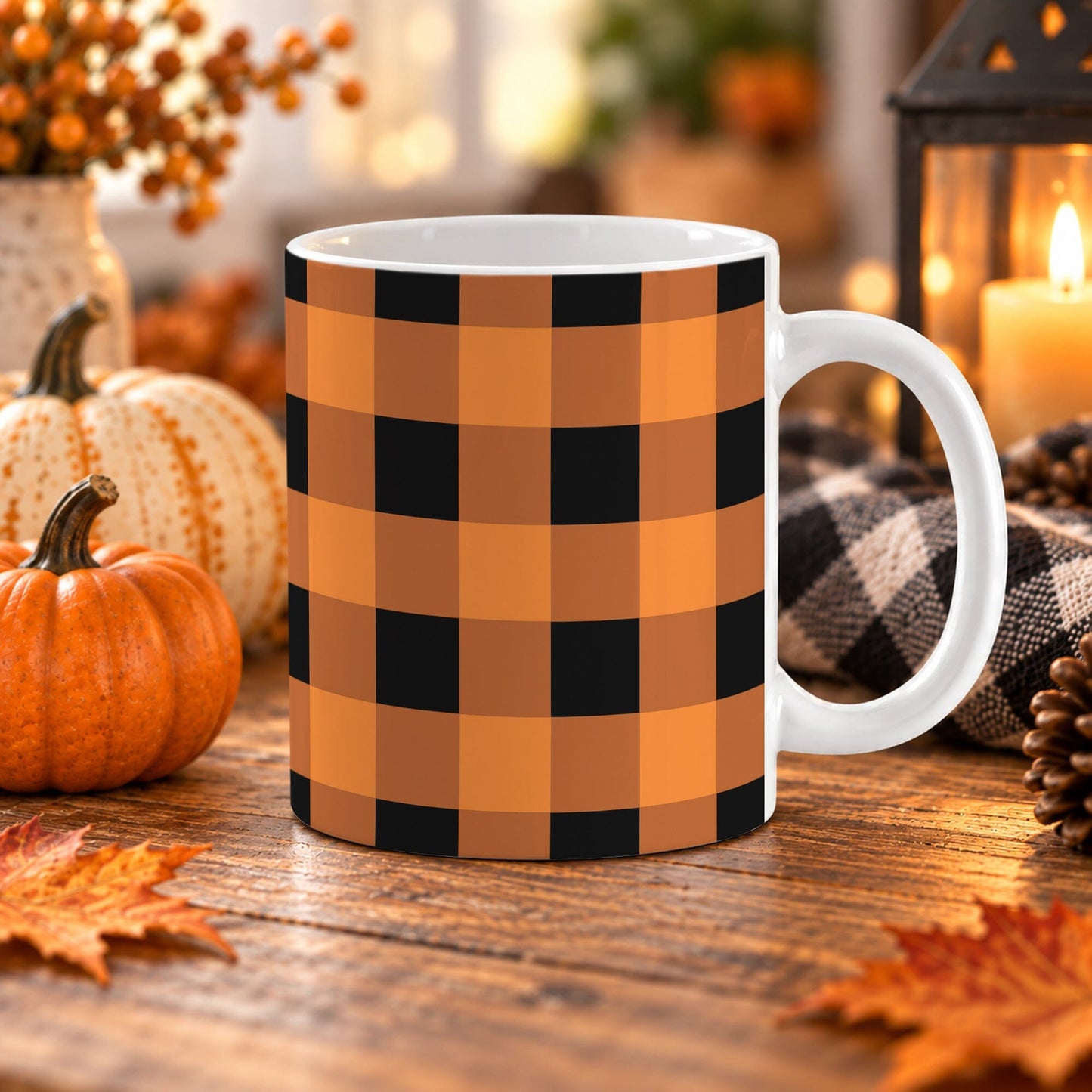 11 oz orange and black buffalo plaid coffee mug with large checkered pattern wrapping around the mug up to the handle. The mug is on a wooden table with fall decor around it.