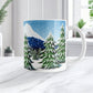 Mug with a winter scene of trees and snow on a white countertop