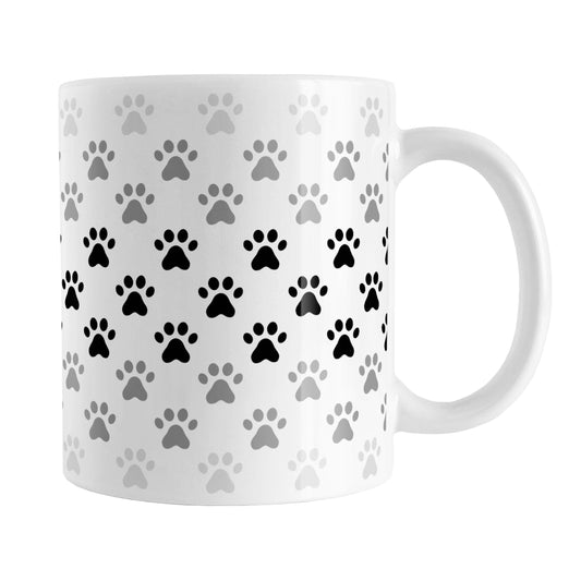 Paw Prints in Black Mug (11oz) at Amy's Coffee Mugs. A ceramic coffee mug designed with paw prints in different shades of black and gray, with black across the middle and a lighter gray along the top and bottom, in a pattern that wraps around the mug to the handle.
