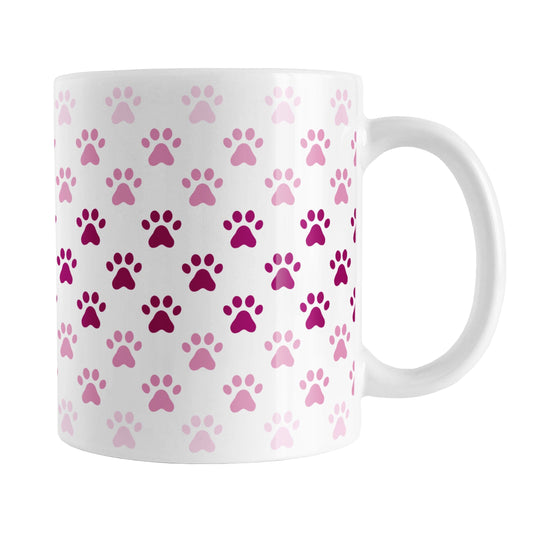 Paw Prints in Pink Mug (11oz) at Amy's Coffee Mugs. A ceramic coffee mug designed with paw prints in different shades of pink, with the darker pink color across the middle and the lighter pink along the top and bottom, in a pattern that wraps around the mug to the handle.