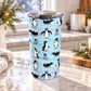 20 oz penguin tumbler cup with adult and baby penguins across a light blue winter pattern with snowflakes and snowy teal and purple bands, on a granite countertop in a kitchen with light rustic winter decor including pine cones, pine boughs, and a cozy blanket.