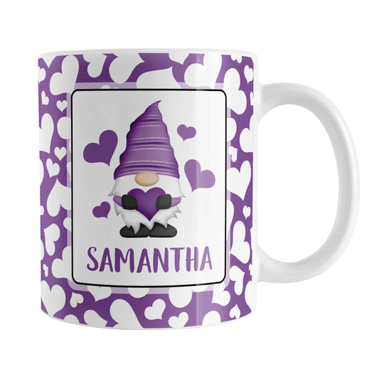 Personalized Cute White Hearts Purple Gnome Mug (11oz) at Amy's Coffee Mugs. A ceramic coffee mug designed with an adorable purple gnome holding a purple heart in a white rectangle on both sides of the mug over a pattern of cute white hearts over a purple background that wraps around the mug to the handle. Your personalized name is custom printed in an all-capital letters purple font below the heart-holding gnome.