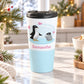 15 oz personalized penguin travel mug with parent and baby penguin, pink hearts, blue accents, and custom name in pink, on a granite countertop in a bright kitchen with light rustic winter decor including pine cones, pine boughs, lights, and a cozy blanket.