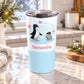 20 oz personalized penguin tumbler cup with parent and baby chick, pink hearts, custom name in pink, and soft blue design, on a granite countertop in a kitchen with light rustic winter decor including pine cones, pine boughs, and a cozy blanket.