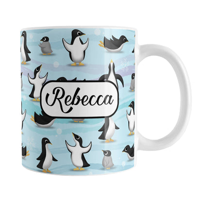 Personalized Penguin Parade Pattern Mug (11oz) at Amy's Coffee Mugs. A ceramic coffee mug designed with a fun penguin parade pattern featuring a variety of penguins and baby penguins over an Antarctic background with waves of blue, turquoise, and purple colors with hints of snowflakes that wraps around the mug. Your name is personalized in a black script font on both sides of the mug over the cute penguin pattern.