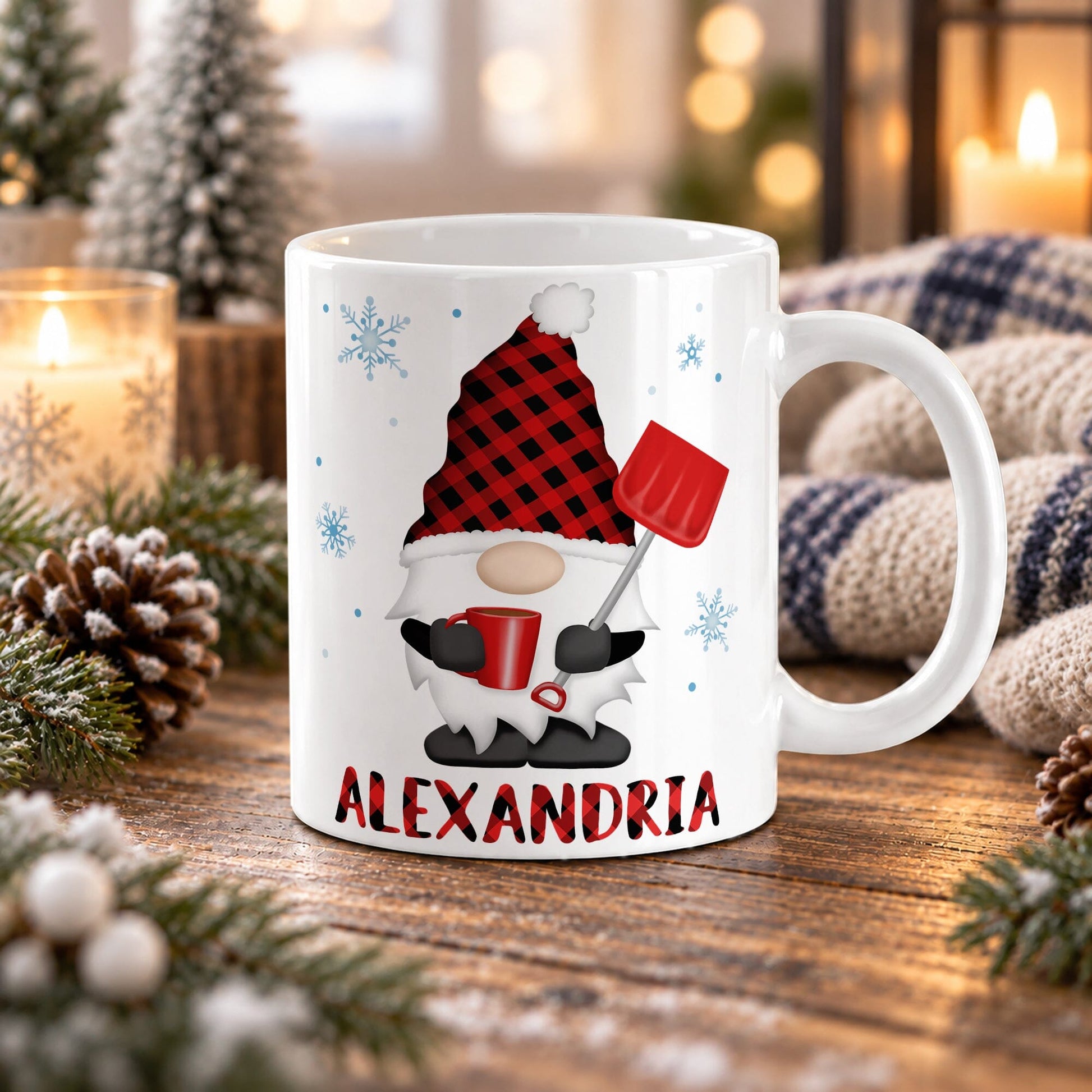 11 oz personalized winter gnome mug with red buffalo plaid hat, red mug, snow shovel, blue snowflakes, and custom plaid name, on a wooden table with winter decor around it including pine cones, pine boughs, candles, and a cozy plaid blanket.