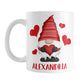 Personalized Red Heart Gnome Mug (11oz) at Amy's Coffee Mugs. A ceramic coffee mug designed with an illustration of an adorable gnome with a red pointed hat, holding a big red heart, with bold red hearts around it. Below the gnome is your personalized name custom printed in a cute red font. This charming gnome and personalized name are printed on both sides of the mug.