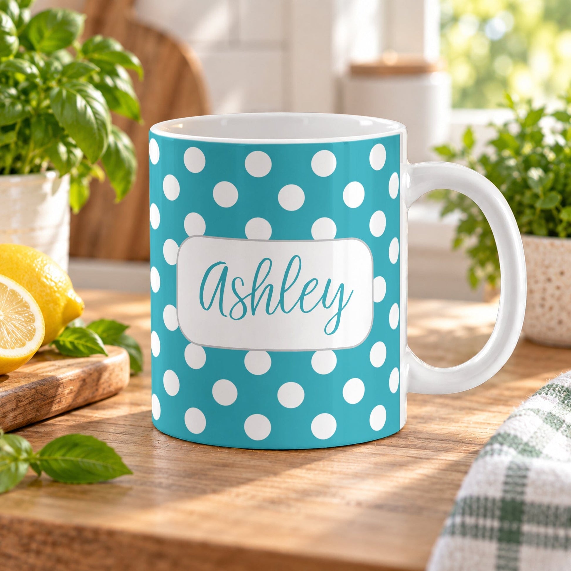 11 oz personalized turquoise polka dot mug with white dots and custom name on both sides, displayed on a wooden table in a bright kitchen with green plants and lemons on a wooden cutting board.