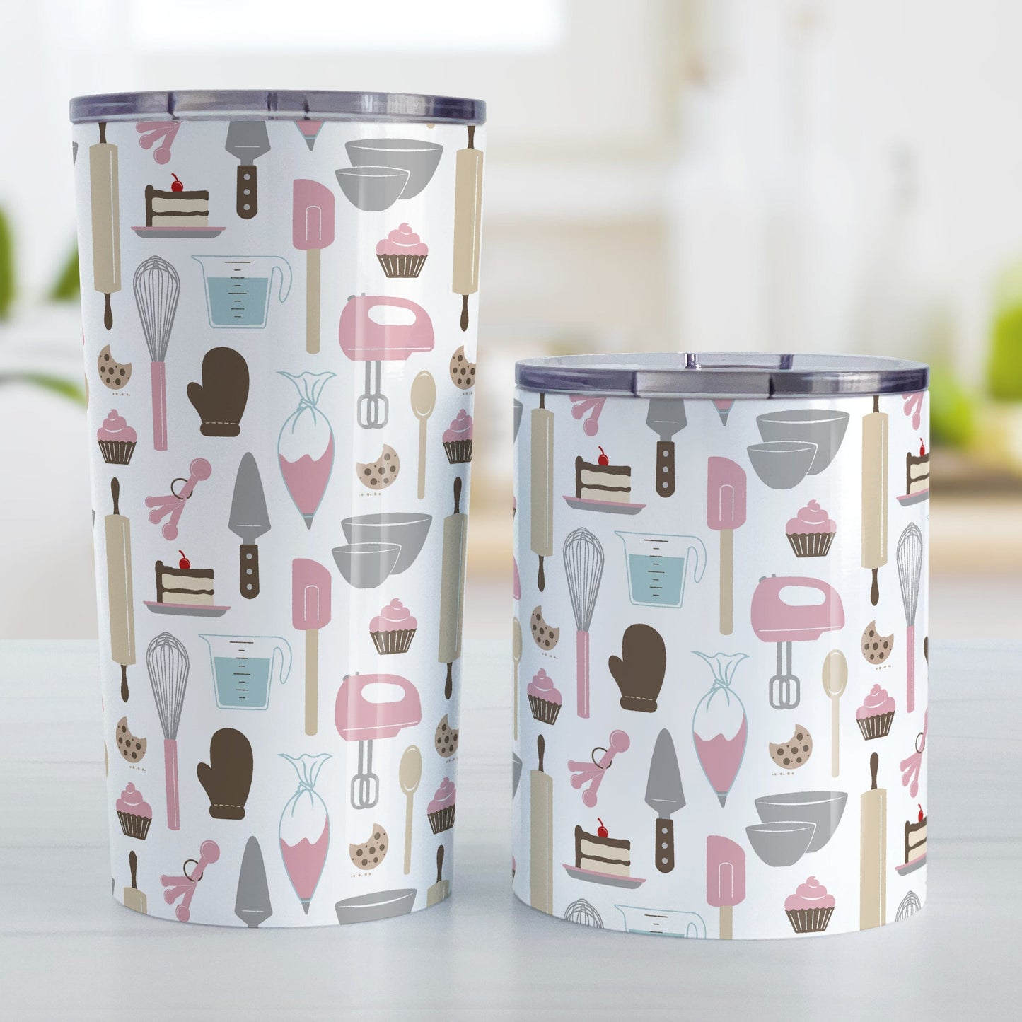 Pink Baking Pattern Tumbler Cups (20oz or 10oz) at Amy's Coffee Mugs. Stainless steel tumbler cups designed with a pattern of baking tools like spatulas, whisks, mixers, bowls, and spoons, with cookies, cupcakes, and cake all in a pink, gray, brown, and beige color scheme that wraps around the cups. Photo shows both sized cups on a table next to each other. 