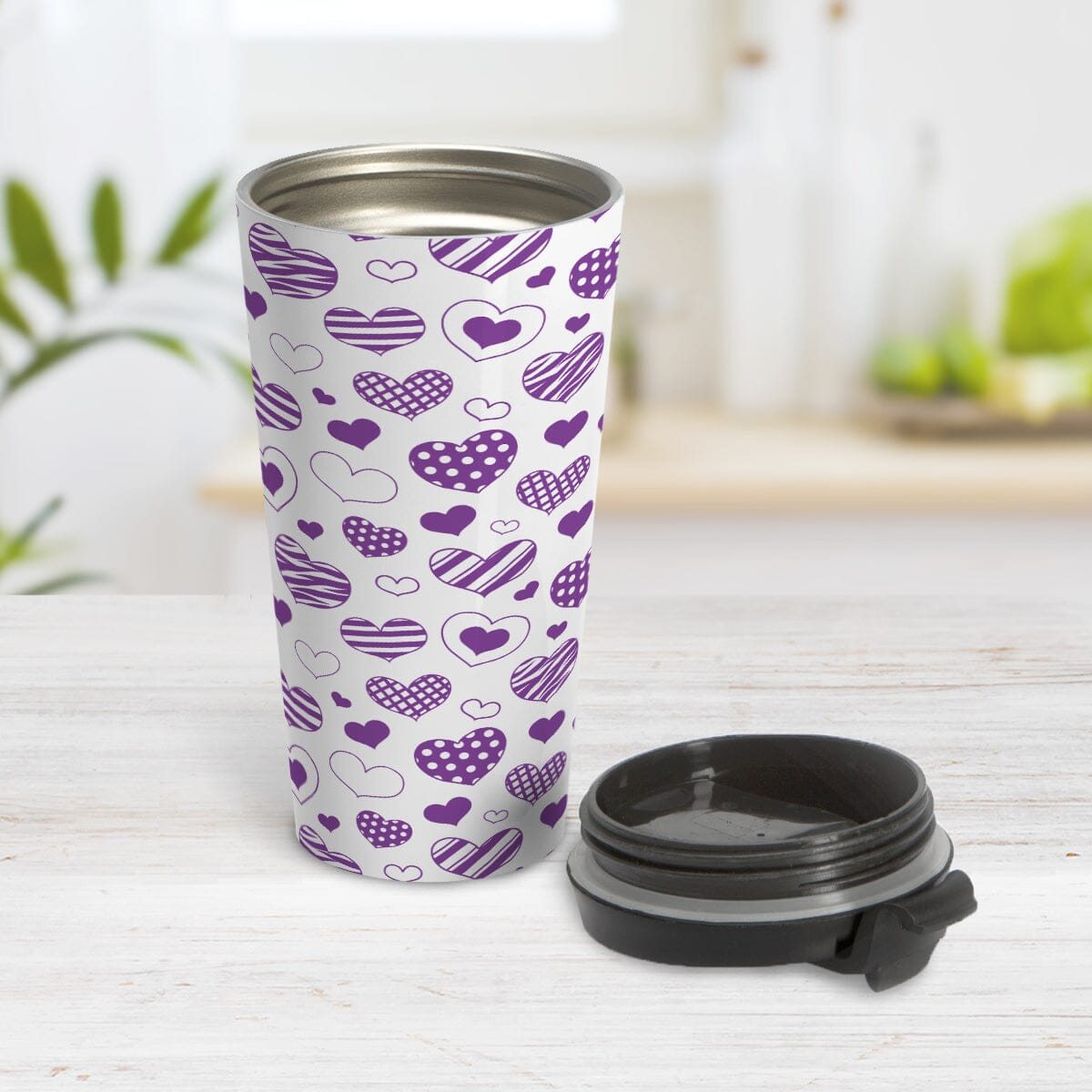 Purple Heart Doodles Travel Mug (15oz) at Amy's Coffee Mugs. A stainless steel travel mug designed with hand-drawn purple heart doodles in a pattern that wraps around the travel mug. This cute heart pattern is perfect for Valentine's Day or for anyone who loves hearts and young-at-heart drawings. Photo shows the travel mug open with the lid on the table beside it.