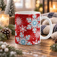 11 oz red winter mug with large aqua blue and white snowflakes, dark red snowflakes, and smaller accents across the pattern, shown on a wooden table with winter decor around it.