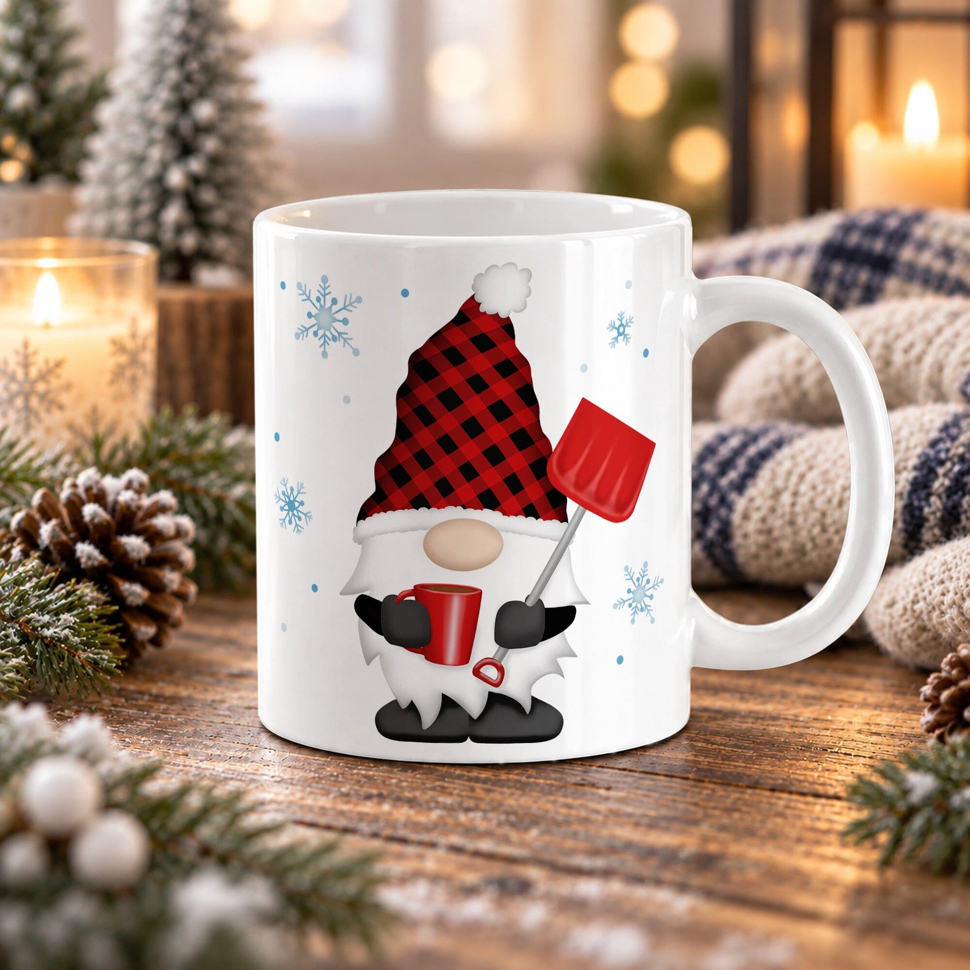 An 11 oz white ceramic mug featuring a festive holiday winter gnome design with a red and black buffalo plaid hat, white beard, black shoes, and a red snow shovel, set on a wooden table surrounded by candles, pinecones, and a cozy knit blanket.