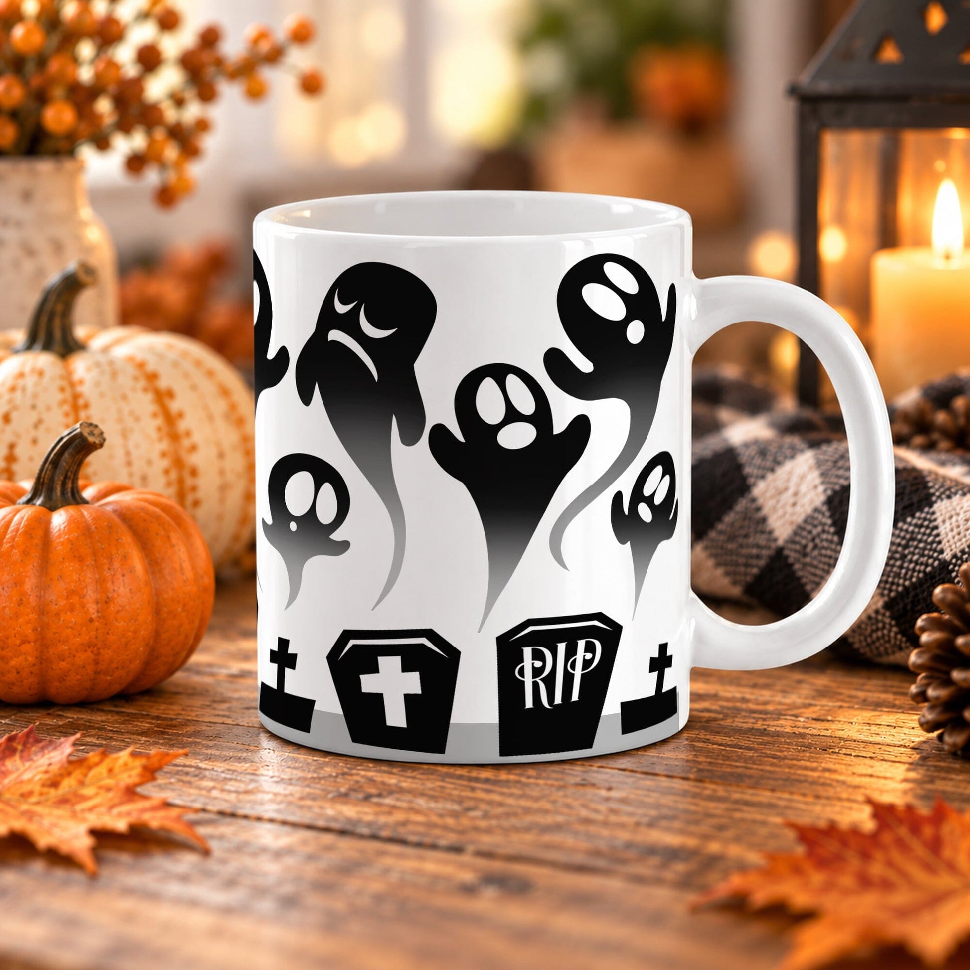 White 11 oz ceramic Halloween mug with black rising ghosts, gravestones, crosses, coffin-shaped markers, and RIP cemetery details, on a wooden table with fall decor including pumpkins, autumn leaves, a candle lantern, and a cozy checkered blanket.