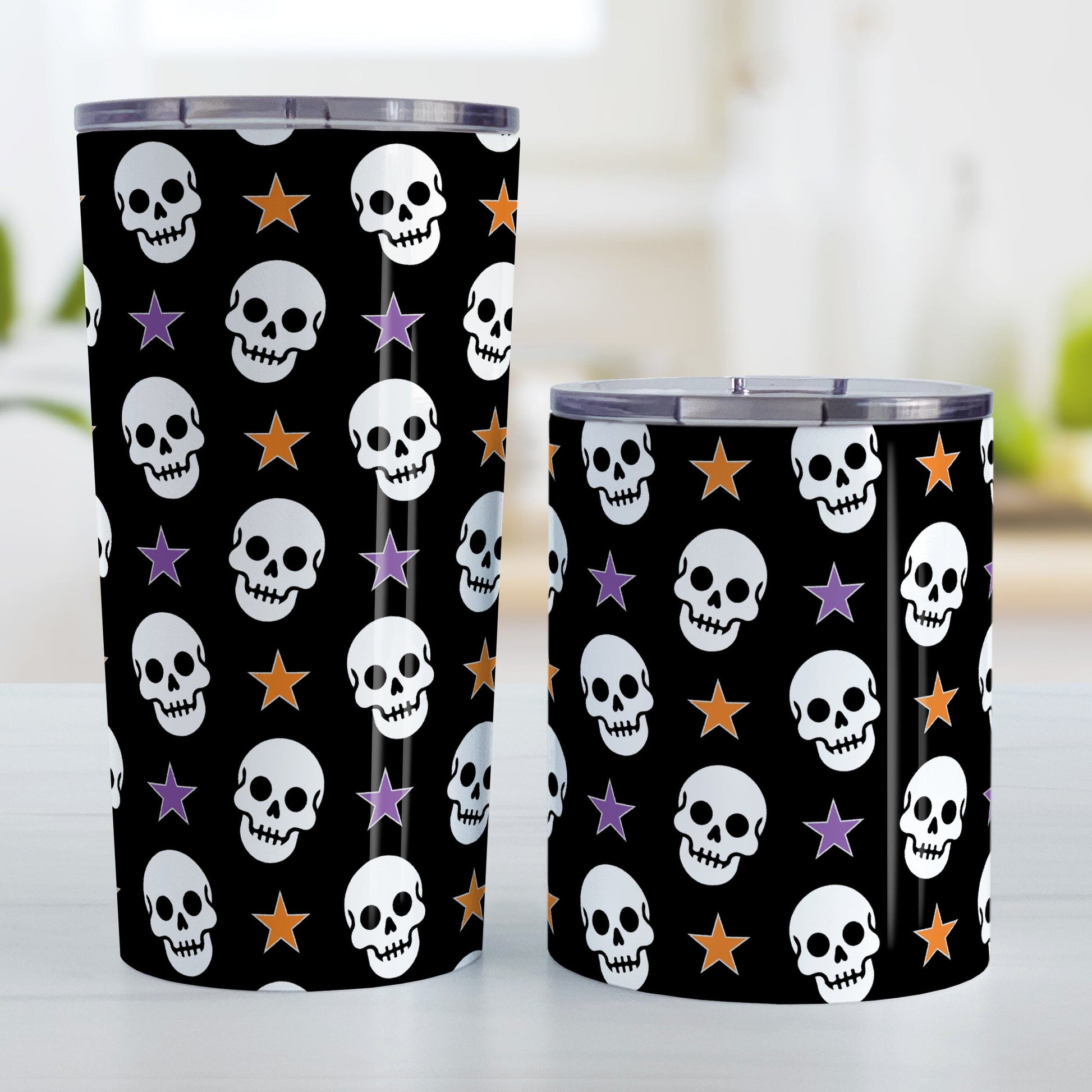 Skulls and Stars Halloween Tumbler Cup (20oz or 10oz) at Amy's Coffee Mugs. A tumbelr cup designed with white skulls and stars in orange and purple over a black background color in a pattern that wraps around the cup. Photo shows both sized cups on a table next to each other.