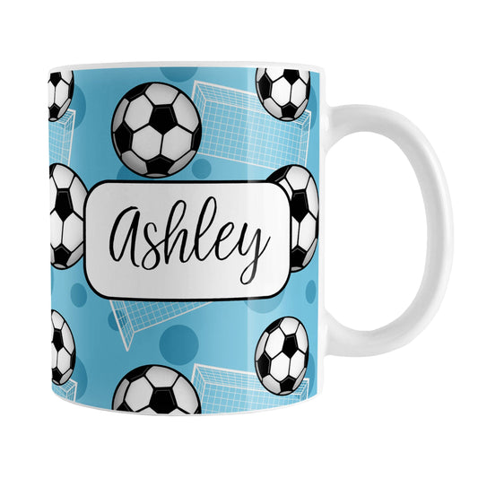 Soccer Ball and Goal Personalized Blue Soccer Mug (11oz) at Amy's Coffee Mugs. A ceramic coffee mug designed with a pattern of soccer balls and white soccer goals over a blue background with blue circles. Your personalized name is custom-printed in a fun black script font on both sides of the mug over the soccer pattern. 