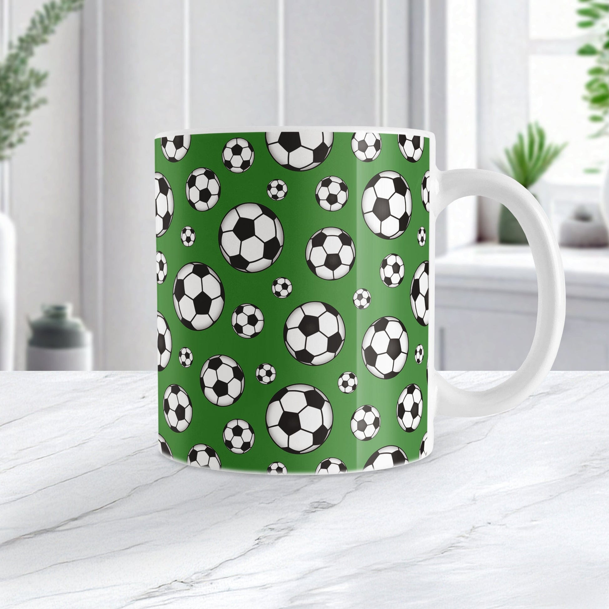 11oz white ceramic mug with a design of soccer balls over dark green, on a marble countertop