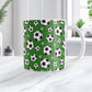 11oz white ceramic mug with a design of soccer balls over dark green, on a marble countertop