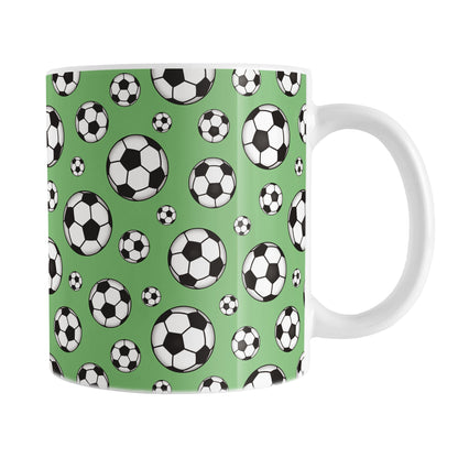 11oz white ceramic mug with a design of soccer balls over green
