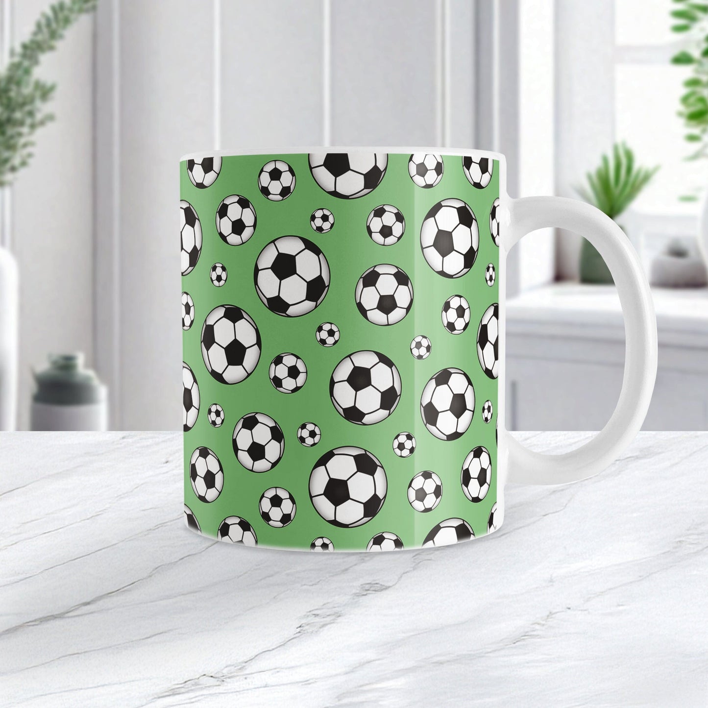 11oz white ceramic mug with a design of soccer balls over green, on a marble countertop