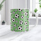11oz white ceramic mug with a design of soccer balls over green, on a marble countertop