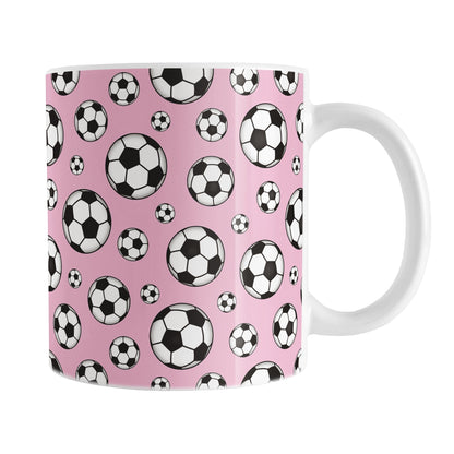 11oz white ceramic mug with a design of soccer balls over pink